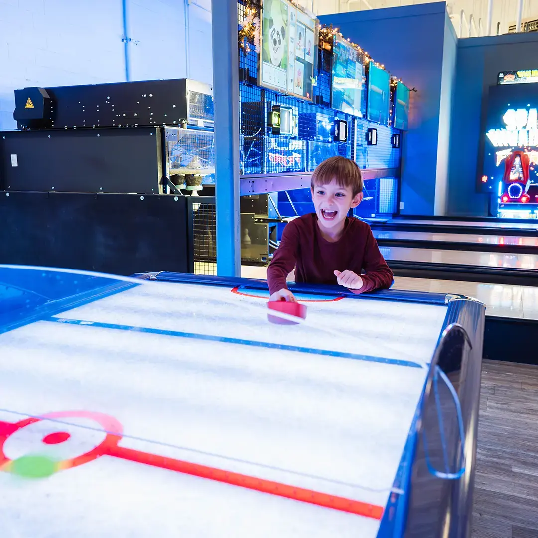 a kid playing air hockey 